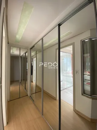 Hall de entrada com piso de madeira e divisórias de vidro.