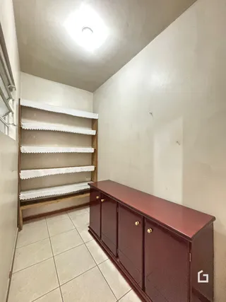 Vista interna de um corredor com estantes de madeira e um móvel longo.