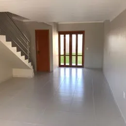 Hall de entrada com escadaria e porta de madeira em um imóvel.