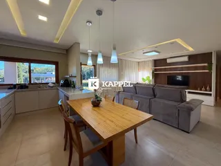 Sala de estar ampla com mesa de jantar de madeira e sofá grande em um ambiente bem iluminado.