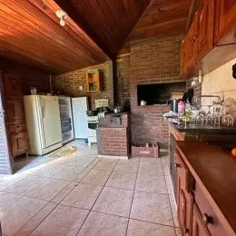 Foto interna de uma cozinha com teto de madeira e paredes de tijolo aparente.