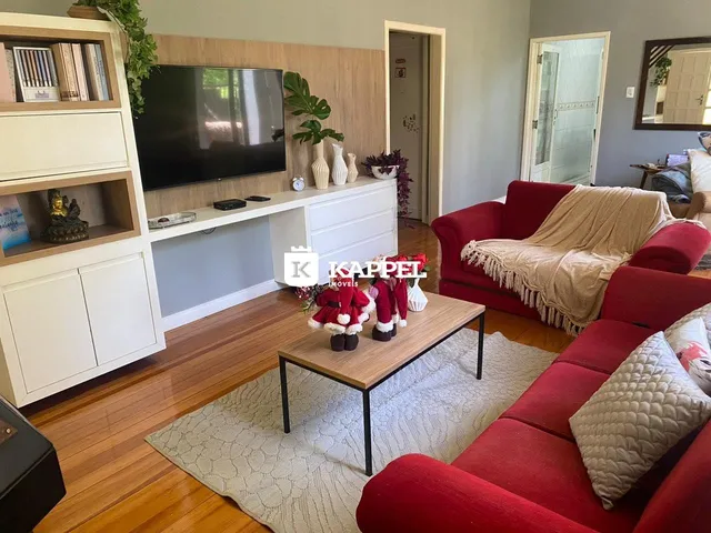 Sala de estar com sofá vermelho e móveis de madeira clara.