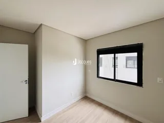 A sala apresenta paredes claras e piso de madeira.