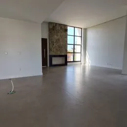 Ambiente interno amplo com paredes brancas e uma lareira visível.