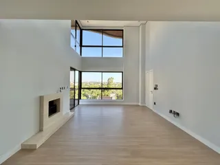 Sala de estar ampla com piso de madeira e grandes janelas.