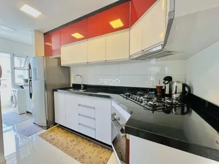 A cozinha moderna apresenta armários brancos e detalhes em vermelho.