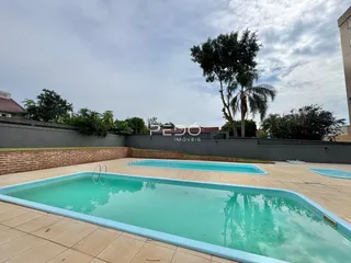 Piscina externa em uma área residencial com muro de tijolos.