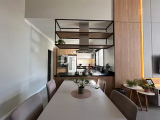 Vista interna de uma sala de jantar moderna com mesa de madeira e decoração contemporânea.