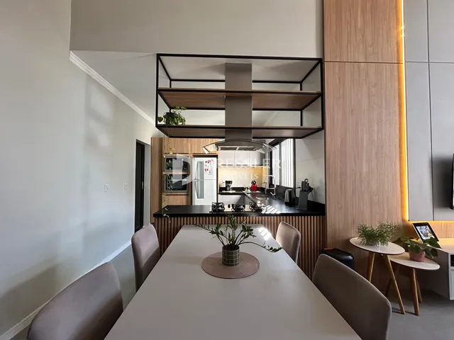 Vista interna de uma sala de jantar moderna com mesa de madeira e decoração contemporânea.