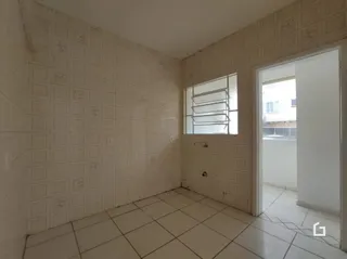 Interior de um cômodo com paredes e piso de cerâmica branca.