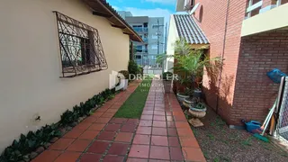 Vista externa de uma residência com jardim e calçada de tijolos.