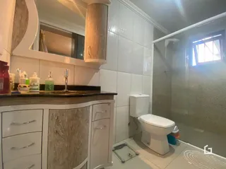 Foto de um banheiro interno com revestimento branco e louças sanitárias.