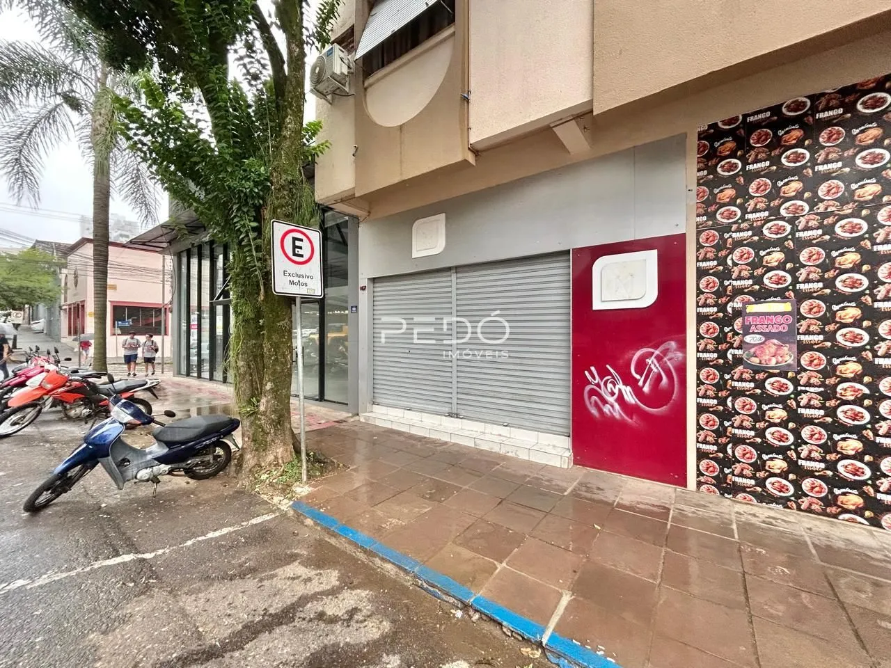Fachada de um imóvel em Lajeado, Brasil, com uma porta de garagem e publicidade na parede.