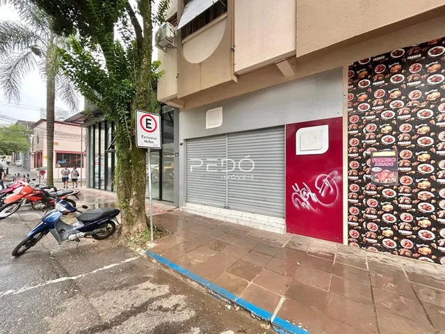 Fachada de um imóvel em Lajeado, Brasil, com uma porta de garagem e publicidade na parede.