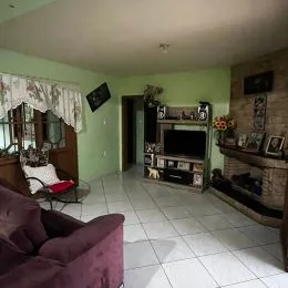 Sala de estar com sofá e televisão em ambiente interno.