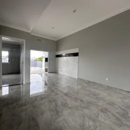 Ambiente interno amplo com piso claro e paredes cinzas.