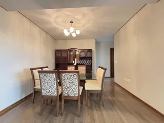 Ambiente interno de uma sala com mesa de jantar e armário de madeira.