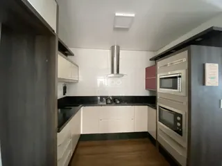 Foto da cozinha com armários brancos e bancadas escuras.