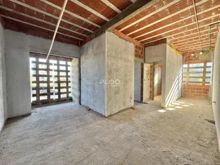 Interior de uma área em construção com paredes de tijolo aparente e teto de madeira.