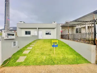 Vista da fachada de uma residência com jardim gramado e cerca.