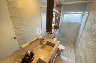 Vista de um banheiro com bancada de mármore e revestimento branco.