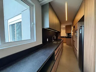 Cozinha moderna com armários escuros e bancadas escuras.