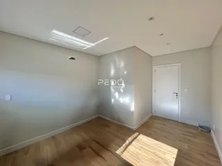Ambiente interno de uma sala com piso de madeira clara e paredes brancas.