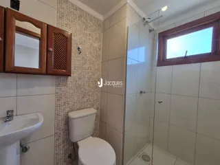 Foto de um banheiro com revestimento cerâmico e box de vidro.