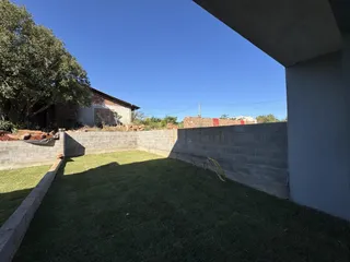 Vista de um quintal gramado com muro de tijolos.