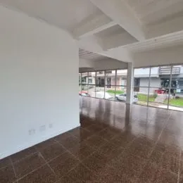 Vista interna de um ambiente com piso escuro e estrutura de teto clara.