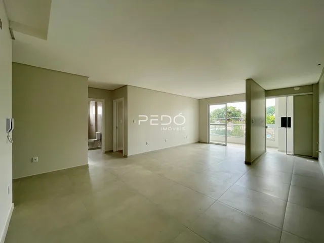 Vista interna de uma sala ampla com piso claro e paredes neutras.