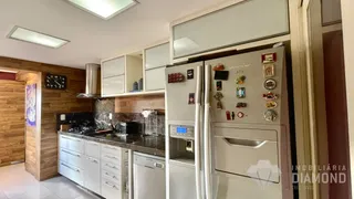 Foto de uma cozinha com armários brancos e bancadas escuras.
