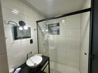 Banheiro com box de vidro e revestimento cerâmico branco.