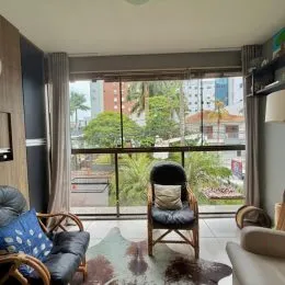 Sala de estar com grandes janelas que oferecem uma vista para a vegetação externa.