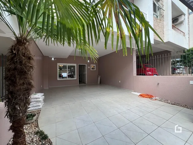 Vista externa de um pátio com piso de cerâmica e vegetação.
