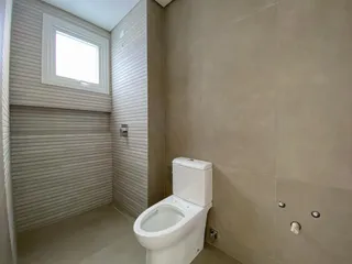Foto interna de um banheiro com revestimento de azulejos claros.
