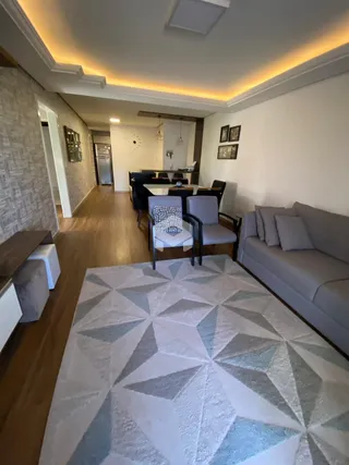 Sala de estar com piso de madeira e tapete estampado.
