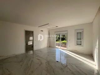 Sala ampla com piso de mármore claro e paredes brancas.