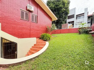 Vista da fachada de uma residência com parede de tijolos vermelhos e jardim gramado.