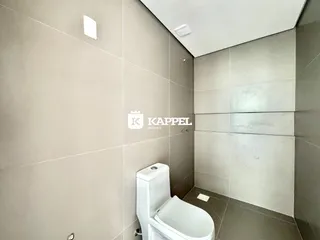Foto de um banheiro com revestimento de azulejos claros e um vaso sanitário branco.