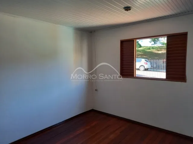 Foto interna de um cômodo com piso de madeira e janela.