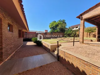 Vista lateral da fachada de uma residência em Lajeado, Brasil, com muro de tijolos e área externa.