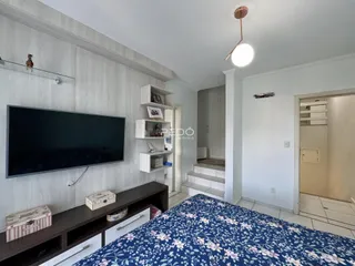 Quarto com cama e televisão em ambiente claro.