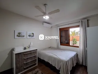 Quarto com cama e cômoda em um apartamento com piso de madeira.
