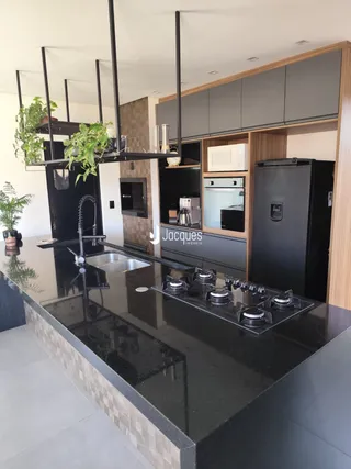 Esta é uma foto de uma cozinha moderna com armários escuros e bancada preta.