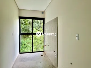 Foto de um corredor interno com uma grande janela que oferece vista para a vegetação externa.