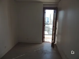 Hall de entrada com parede branca e porta de vidro.