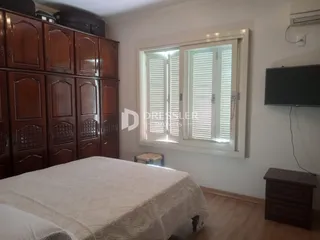 Quarto com armário de madeira e janela com persianas.