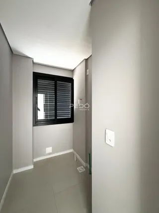 Passagem interna de uma residência com piso claro e paredes brancas.