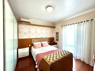 Quarto com cabeceira de madeira e janela iluminada.